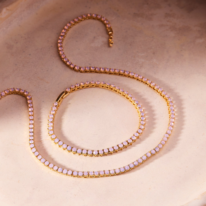 Gold necklace with pink gemstones on a beige background