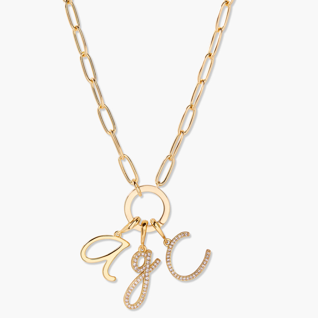 Gold-tone Waverly Initial Charm Necklace with a ring clasp holding three script-letter initial charms, one pavé crystal-set, on a chain.