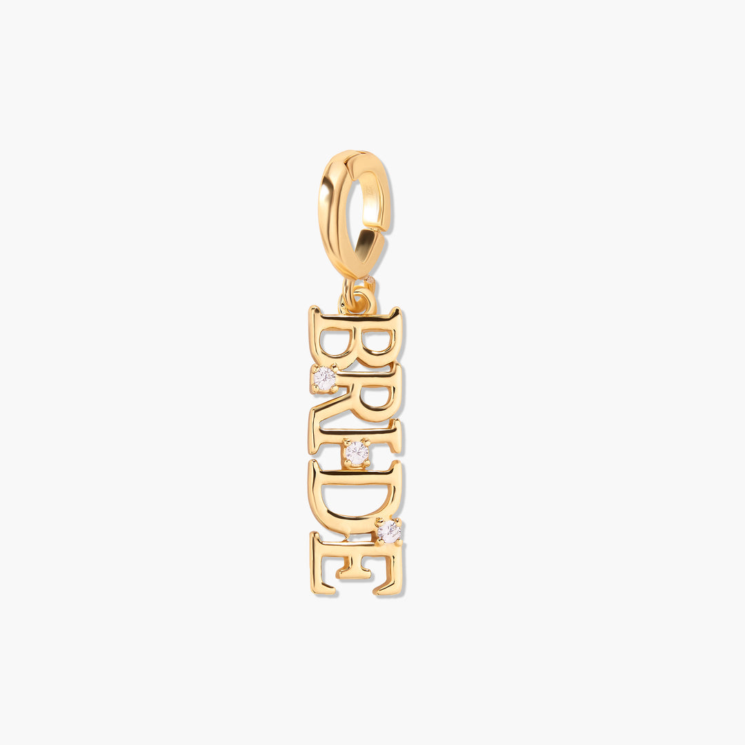 Gold-tone Effie Bride charm with vertical block lettering and three small round white stone accents, suspended from a ring clasp.