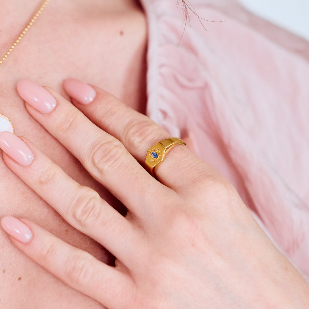  Birthstone Signet rings with hexagonal faces and starburst engraving, each set with a different-colored marquise stone on a women's hand.