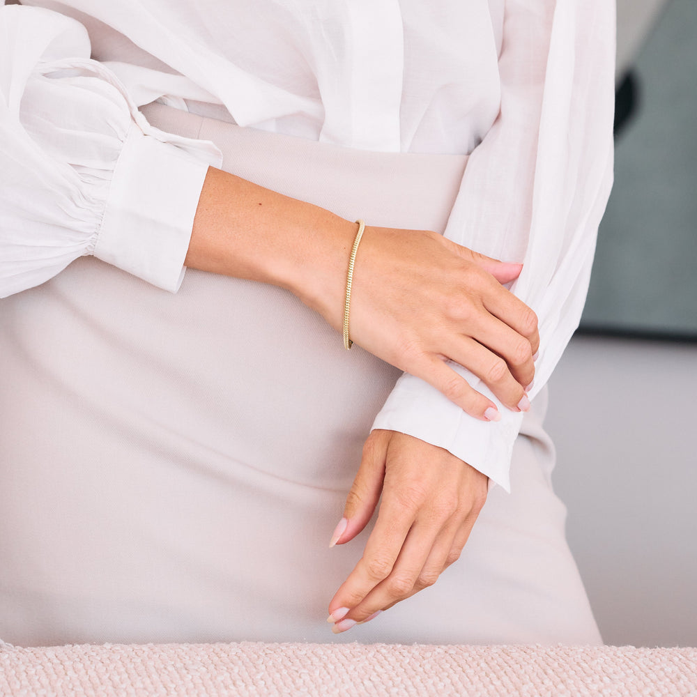  Adele Charm Bracelet with a ridged tubular chain and ring clasp, worn by a model.